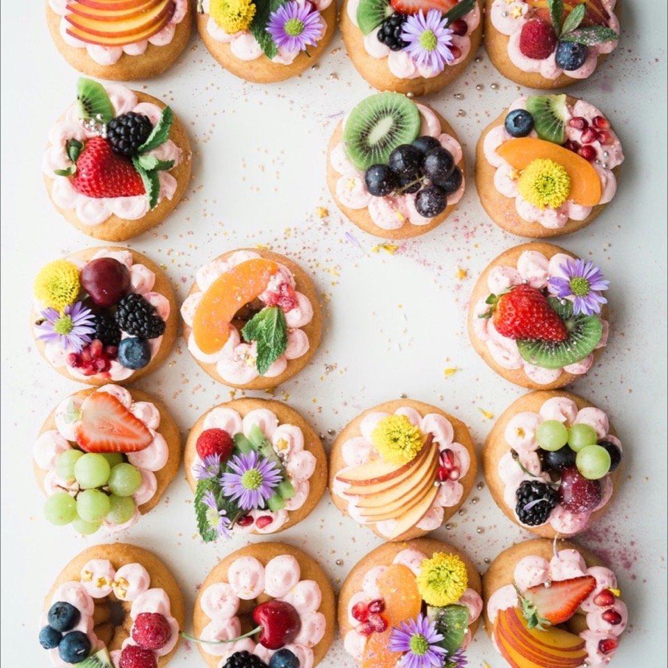 Iced tarts topped with fresh fruit and edible flowers